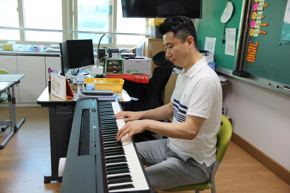 윤학준 교사가 교실에서 피아노를 치고 있다.
