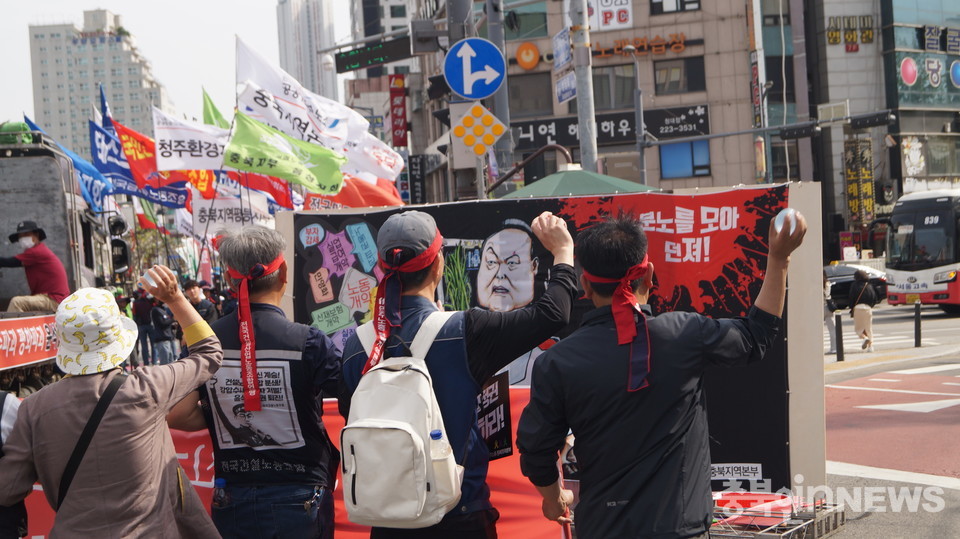 노동조합 대표자들이 현수막에 물풍선을 던지는 퍼포먼스를 진행하고 있다.