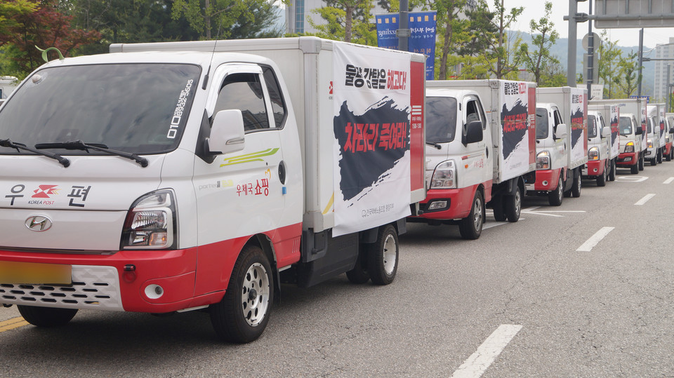 현수막을 건 택배 트럭들이 행진하고 있다. 
