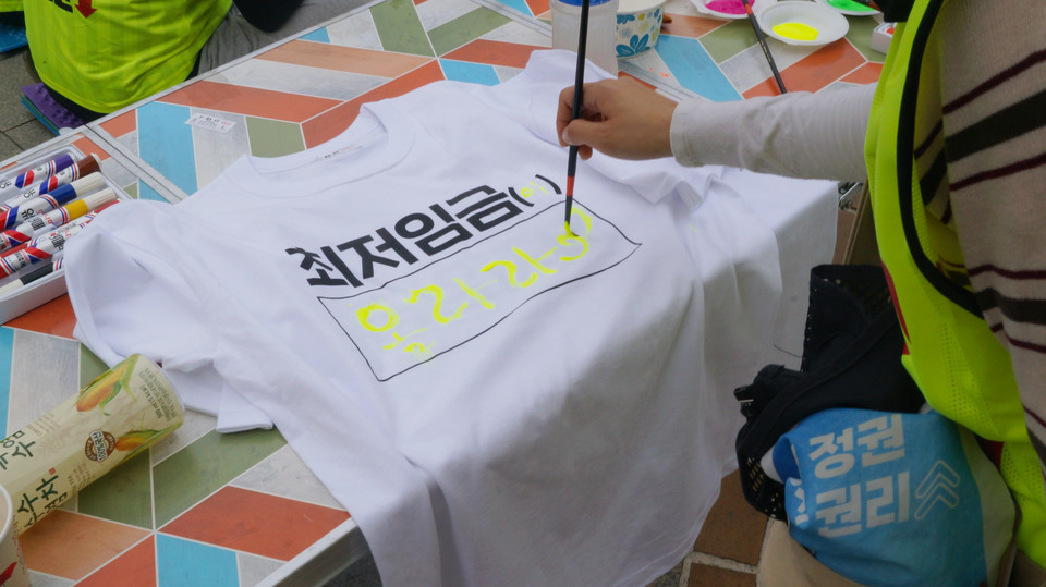 사전행사로 진행된 '최저임금은 ( )다 티셔츠를 채워라'를 진행했다. 문화제 참가자가 '최저임금 올라라'라고 적은 티셔츠.