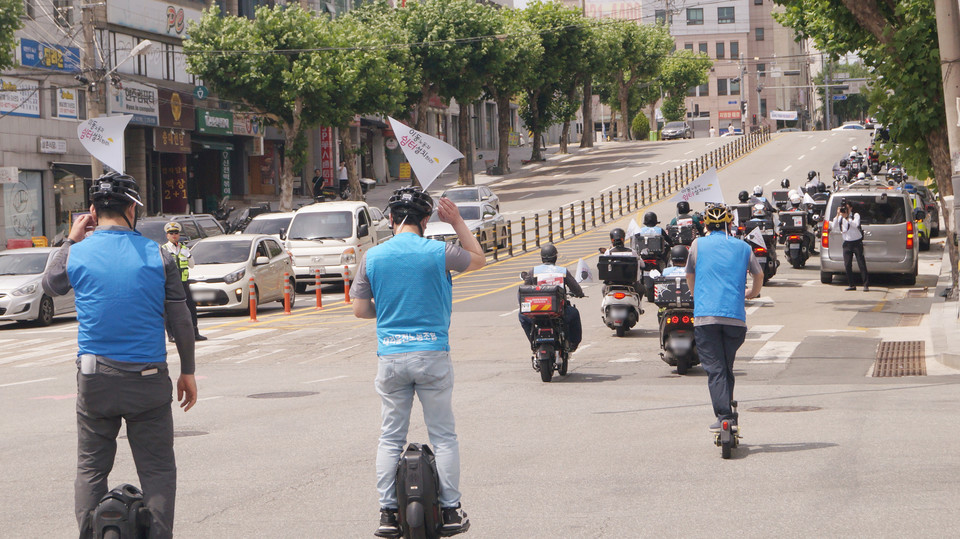 충북대 정문에서 행진하고 있는 플랫폼 노동자들, 배달 노동자 행렬 뒤로 대리운전 노동자가 이동하고 있다. (사진=이종은 기자)