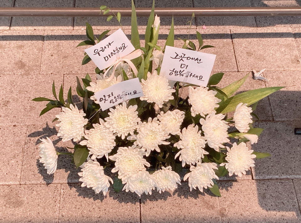 한 시민이 게시판 아래 두고간 국화꽃바구니. (사진=747 모임)