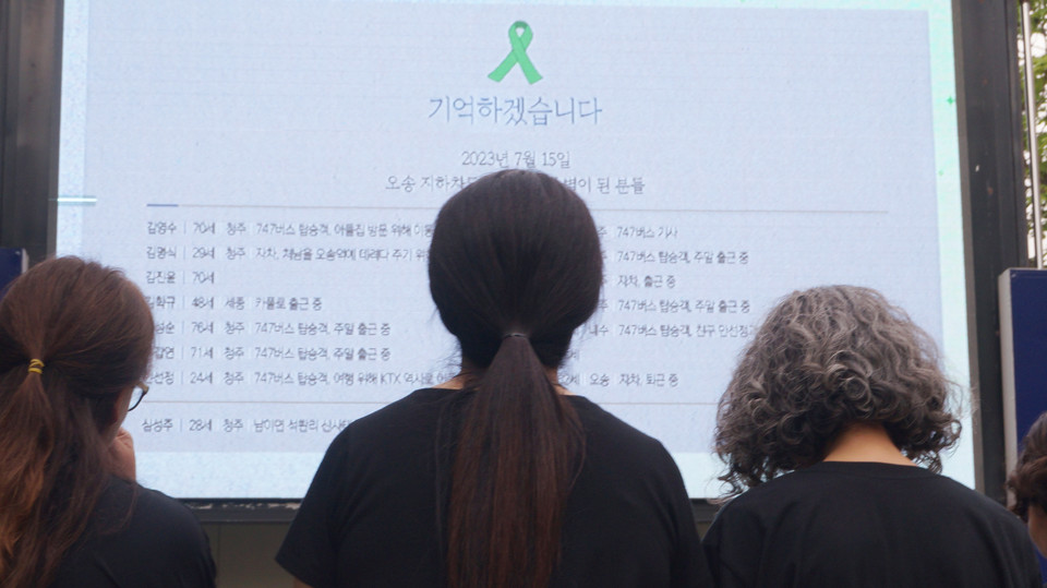 오송참사 1주기 희생자들을 기억하고 참사 진상규명을 촉구하는 결의대회에서 한 참석자가 희생자들에게 헌화한 뒤 오송참사 희생자들의 이름을 바라보고 있다.