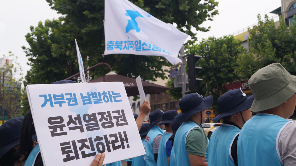 정권 퇴진 피켓을 들고있는 한 참가자 뒤로 선봉대 깃발이 보인다.