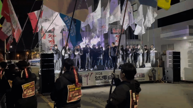 투쟁 깃발을 든 전진대회 참석자들이 단상 위로 오르고 있다.