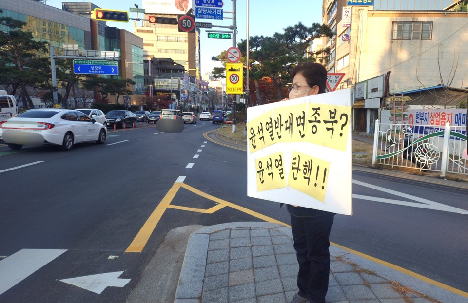집회 참가자가 피켓을 들고 서있다.