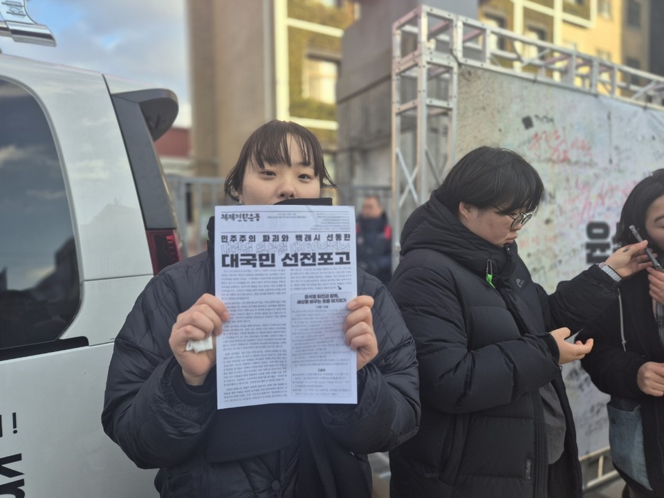 한 학생이 윤석열 대통령을 비판하는 유인물을 들고 시민들에게 윤석열 탄핵을 촉구하고 있다. (사진=김남균 기자)