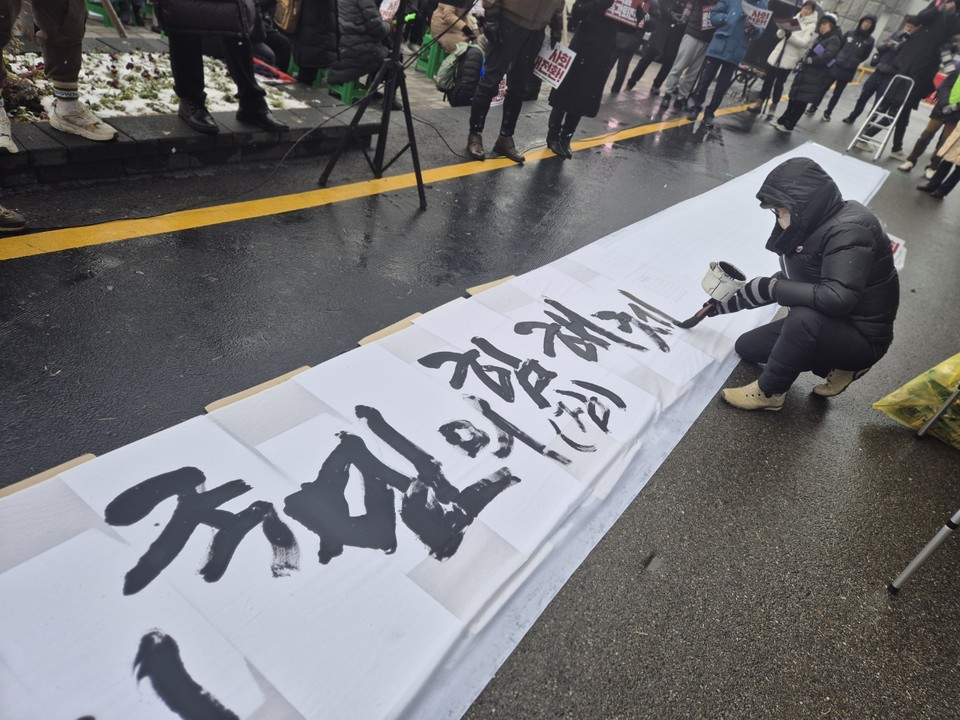 지난 21일 충북도청 서문앞에서 진행된 '윤석열 퇴진 충북시국대회'에서 서예가 김성장 선생이 '국민의힘 해체하라'는 붓글씨를 쓰고 있다. (사진=김남균 기자)