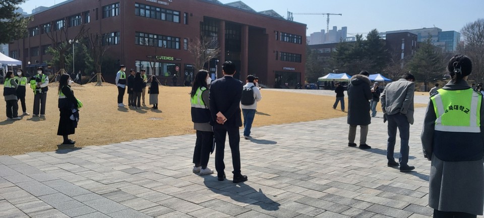 충북대학교 직원들이 '캠퍼스 폴리스'라는 글씨가 씌여진 조끼를 입고 집회 주변을 서성이고 있다.